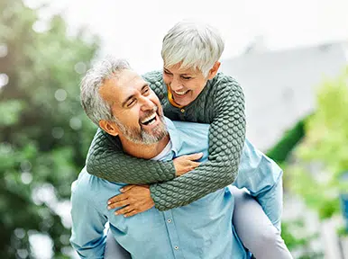 Elevating Your Confidence Older couple laughing outdoors, representing lasting healthy smiles and quality dental care for seniors