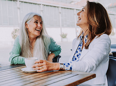 Improving Your Daily Nutrition Two women smiling and talking over coffee, representing comfortable patient experience and friendly dental care