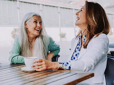Improving Your Daily Nutrition Two women smiling and talking over coffee, representing comfortable patient experience and friendly dental care