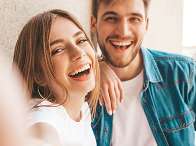 Young couple smiling together, representing happy patients and confident, healthy smiles from dental care