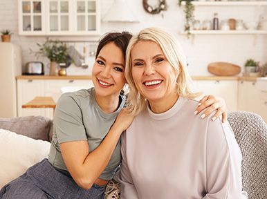 Restoring Your Facial Esthetics Mother and daughter smiling together at home, representing family dentistry and healthy smiles for all ages