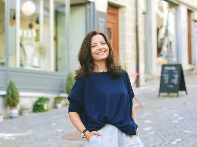 Woman smiling outdoors in city, representing confident, healthy smile and results from cosmetic or general dentistry